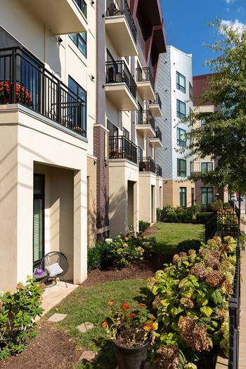 A white building with a balcony and a small garden in front.